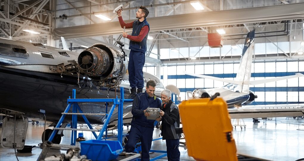 Aircraft mechanics inspect and repair a jet engine inside a spacious hangar.